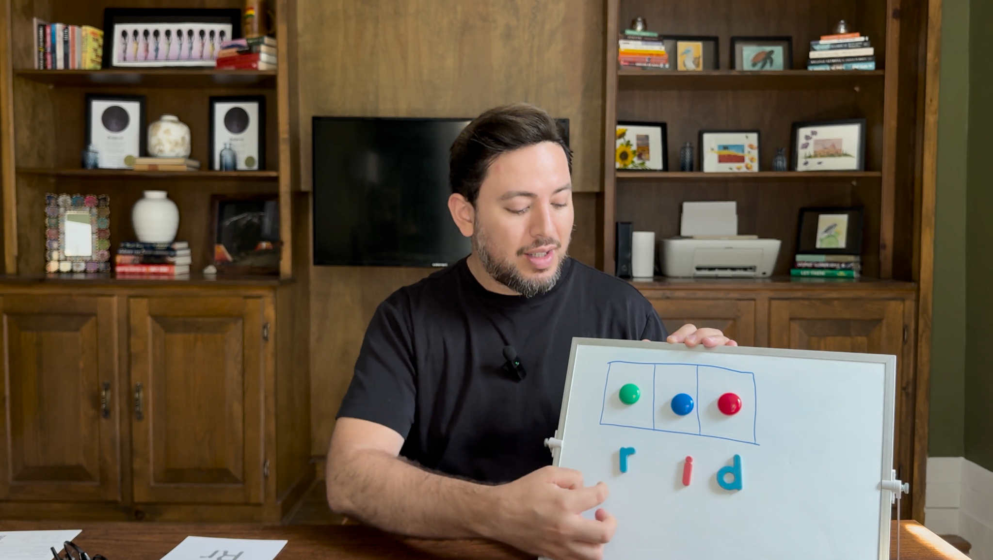 Fabricio enseñando la palabra rid con tres cajas de sonido y las letras magnéticas r, i y d